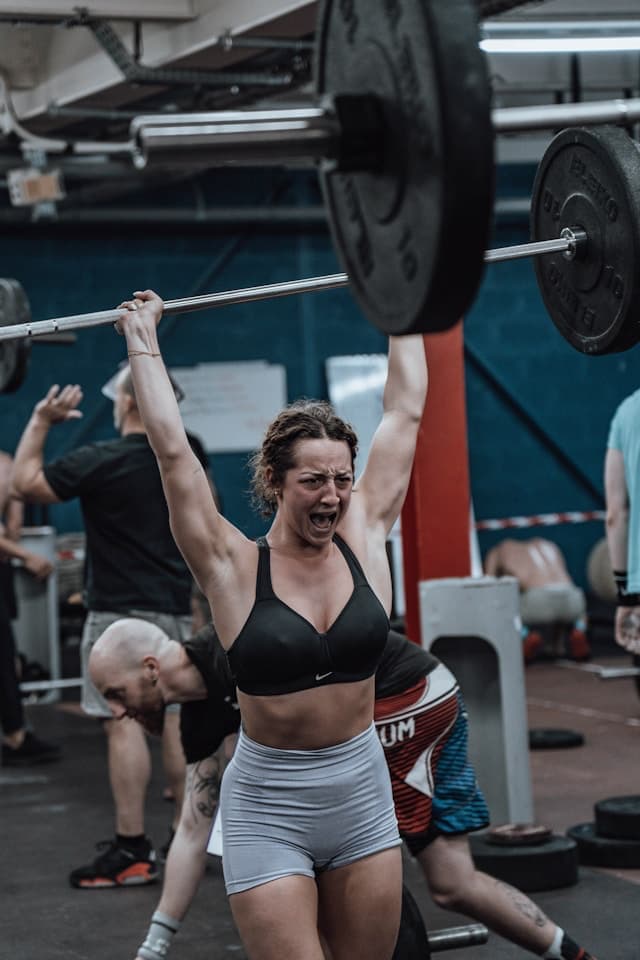 Athlete lifting a barbell overhead in a gym